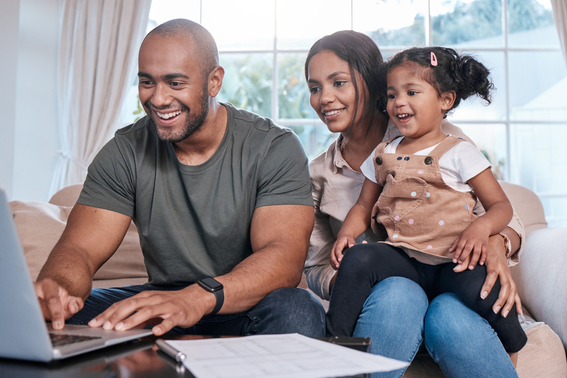 Shot of a couple and their little daughter using a laptop at home